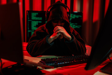 Obraz premium Lone hacker in a dark glowing room hacking data for cyber theft, symbolizing digital crime and online security threats.