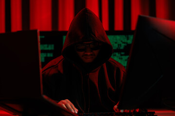 Lone hacker in a dark glowing room hacking data for cyber theft, symbolizing digital crime and...