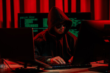 Lone hacker in a dark glowing room hacking data for cyber theft, symbolizing digital crime and...