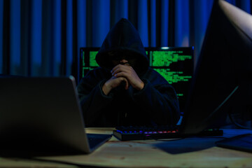 A hacker operates in a dark room, stealing sensitive data through cybercrime — representing one...