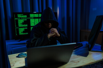 Male hacker in a dark room trying to steal global user data to sell on the dark web, representing...