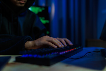 Male hacker in a dark room trying to steal global user data to sell on the dark web, representing...