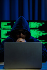Male hacker in a dark room trying to steal global user data to sell on the dark web, representing...