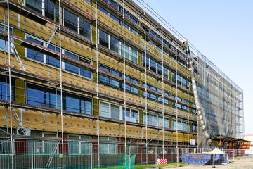Renovation of office building covered in scaffolding and protective net during reconstruction work