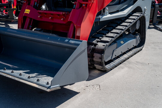 Industrial compact skid steer loader with rubber tracks on hard asphalt in bright day ready for large new construction projects around in the city