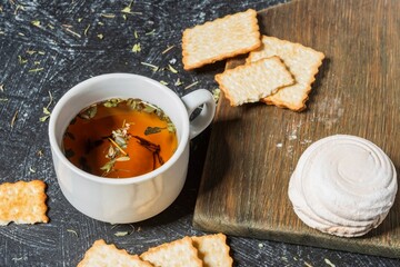 Still life - a cup of herbal tea on the table. Sweet food on a dark background