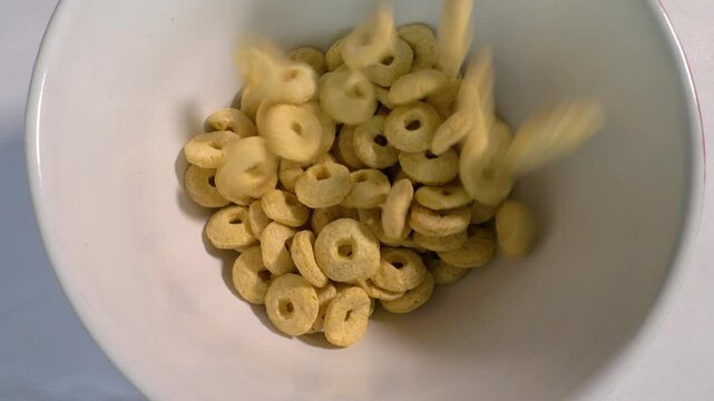 Pour Muesli rings in a plate, top view, ood breakfast in a plate, in slow motion, in slow motion, spinning on a turntable in motion. Close-up.