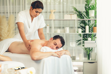 Obraz premium Caucasian couple customer enjoying relaxing anti-stress spa massage and pampering with beauty skin recreation leisure in day light ambient salon spa at luxury resort or hotel. Quiescent