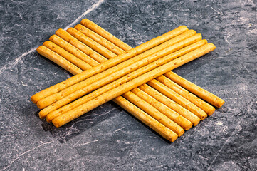 Breadsticks arranged in a cross pattern on stone surface