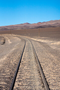 Railroad tracks cutting through the barren landscape of La Puna, Argentina