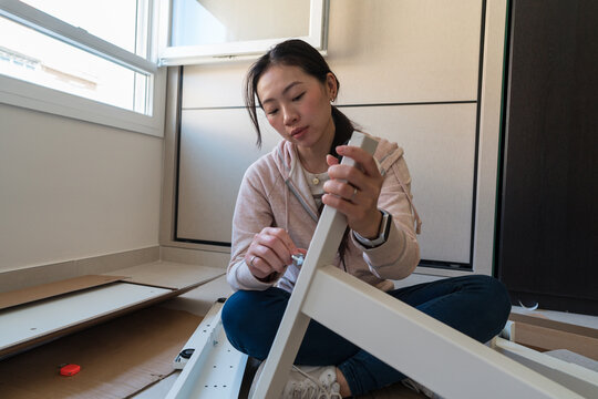 Young woman assembling white desk in living room
