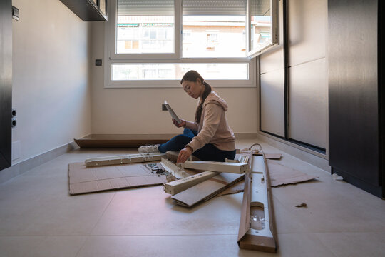 Asian woman assembling desk in bright home setting