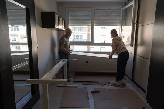 Man and Woman Building a White Desk in a Bright Room