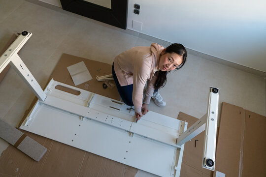 Young woman assembling a white desk at home