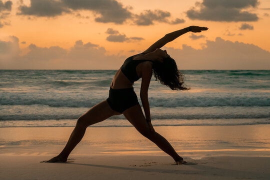 Yoga by the ocean at sunrise with serene sky and waves in Tulum