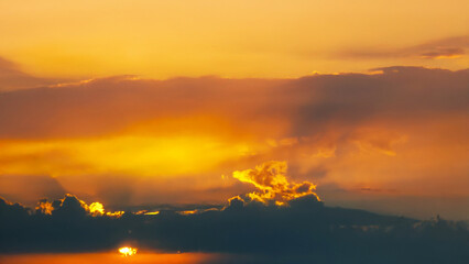 A stunning evening sky with glowing orange and golden clouds against a soft blue background. The illuminated edges of the clouds add depth and drama to the scenery.
