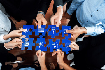 Diverse business team collaboratively assembling puzzle pieces, each featuring icons of advertising and marketing strategies, symbolizing unity and strategic planning for success. Amity