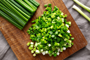 Organic Cut Green Onion Scallions on a Wooden Board, top view.