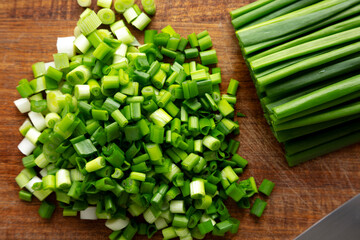 Organic Cut Green Onion Scallions on a Wooden Board, top view.