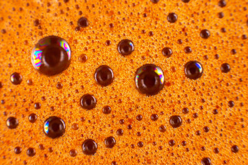 Macro close-up of frothy coffee crema with golden-brown bubbles, showcasing rich texture and reflective surfaces. Perfect for coffee lovers, beverage ads, or food photography