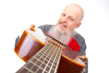 Senior bald man with a thick gray beard poses with an acoustic guitar, dressed in a gray sports shirt, isolated on a white backdrop, highlighting a passionate musical expression.
