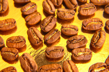 Close-up of roasted coffee beans arranged in an oval on a golden reflective surface, capturing...