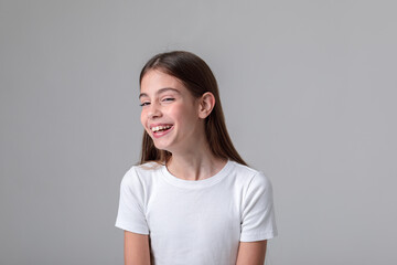 Fototapeta premium Portrait of a beautiful teenage girl with long hair in black leggings and a top in a photo studio on a white background. Different emotions. Emotional shot. Model. Photo model. Photo session.