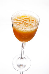 A refreshing glass of freshly squeezed orange juice with a frothy top, served in a elegant clear wine glass against a clean white background. Perfect for food, beverage, and healthy lifestyle themes.