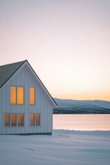 Obraz premium Snow-covered landscape at dusk with a cozy white house and mountains in the background, reflecting warm light from windows