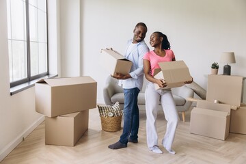 Happy African American Couple Moving into New Apartment Holding Cardboard Boxes