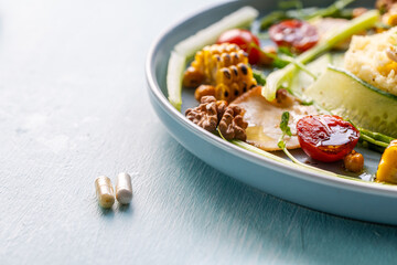 A plate with delicious and healthy food: couscous with vegetables and a plate with pills. Concept: Pills or healthy food.
