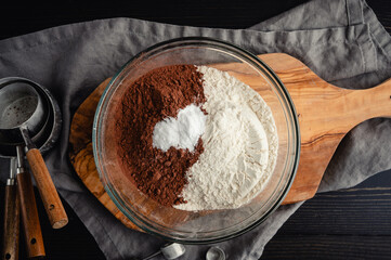 Dry Ingredients for Chocolate Cookies in Glass Bowl: Overhead view of Dutched cocoa powder, all-purpose flour, baking soda, and salt with dry measuring cups