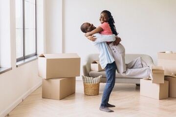 Happy african american couple hugging in new apartment surrounded by cardboard boxes