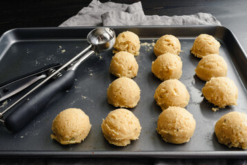 Scoops of Sugar Cookie Dough on a Sheet Pan: Non-stick baking pan with balls of cookie dough and a...