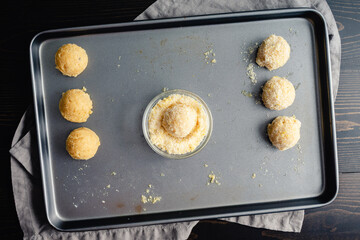 Scoops of Cookie Dough Coated in Lemon Sugar: Directly above a baking pan with a few balls of sugar...