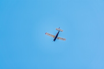 Small ultralight airplane with overhead wing and single propeller flying in sunset sky.