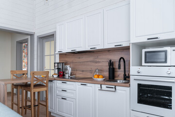 design of large wooden kitchen with white cabinets. Built-in kitchen with upper and lower cabinets,...