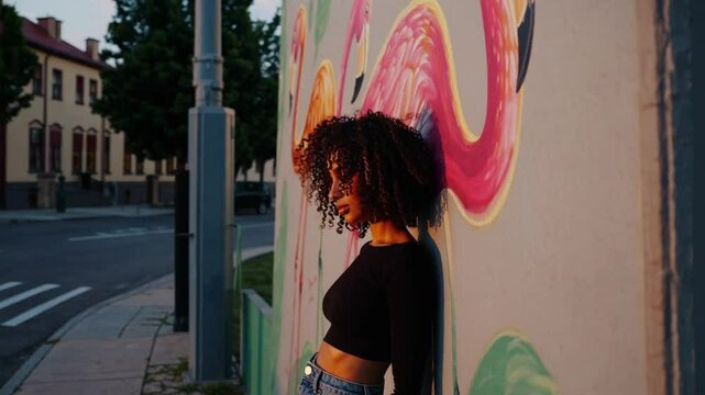 Jeune femme appuy&eacute;e contre un mur color&eacute; au coucher du soleil, ambiance urbaine
