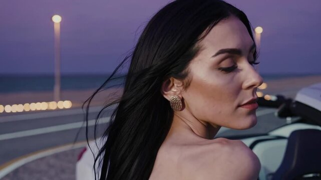 Portrait d&rsquo;une femme au bord de la mer au coucher du soleil, cheveux dans le vent
