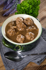 Pork meatballs with noodles in a green bowl.