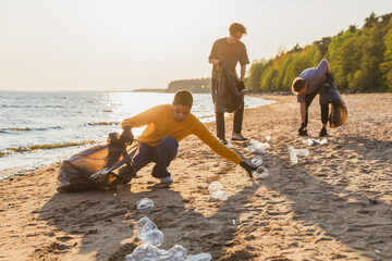 Earth day. Volunteers activists team collects garbage cleaning of beach coastal zone. Woman mans...
