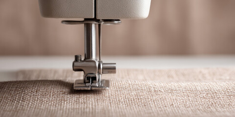 A sewing machine needle is stitching fabric. Concept: sewing and textiles