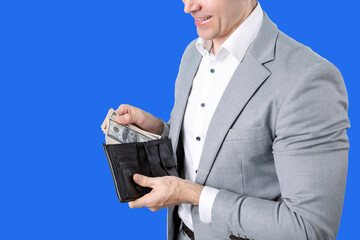 Successful young Businessman Showing Money From Her Wallet on isolated blue background. Finance...