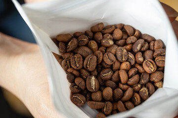 Close-up view of roasted coffee beans inside a white bag, showcasing the rich texture and color of the beans