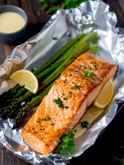 A piece of salmon alongside asparagus on foil, showcasing a healthy meal prep option.