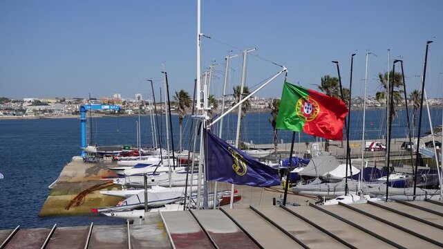 Portuguese Marina with Sailboats Flags and Coastal Cityscape on a Sunny Day