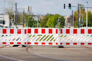 Temporary red-white traffic barricades block access to tram tracks on german city street....