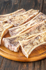 Rustic roasted marrow bones rest on warm wooden board, savory richness revealed