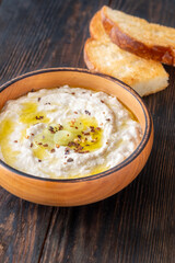 Creamy baba ghanoush in wooden bowl with chili and olive oil