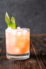 Guava rum punch cocktail with pineapple garnish on moody tropical evening backdrop